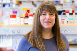 woman with long brown hair and bangs in a lab